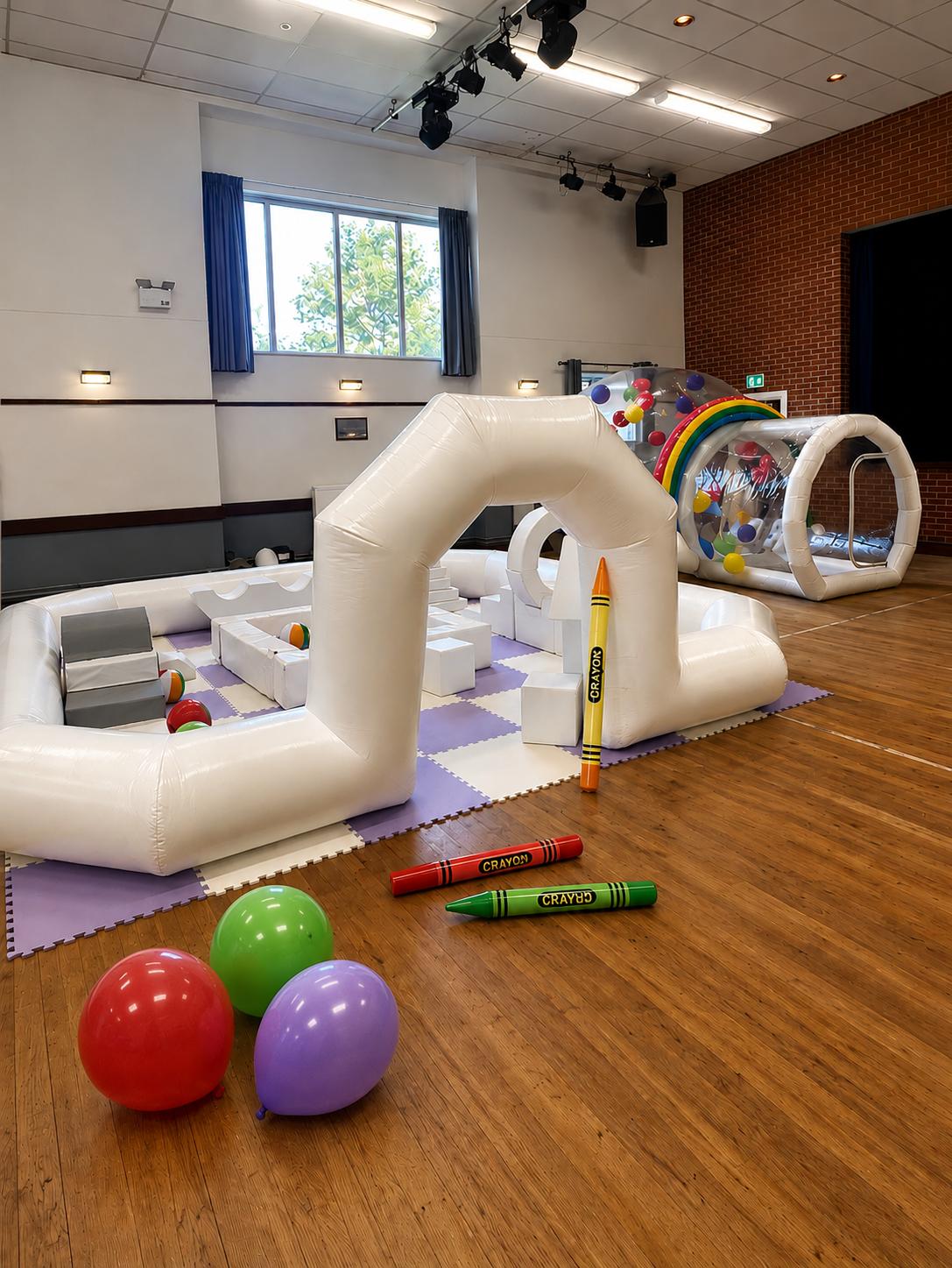 Soft play setup with crayon decorations and rainbow bubble tunnel for school fun day